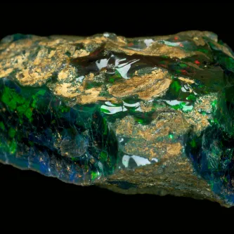 An irregular-shaped opal with blue, green, black, brown, and red coloring.