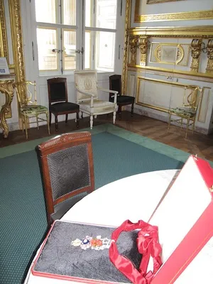 An elaborate piece of jewelry on a table in a room with gilded white walls