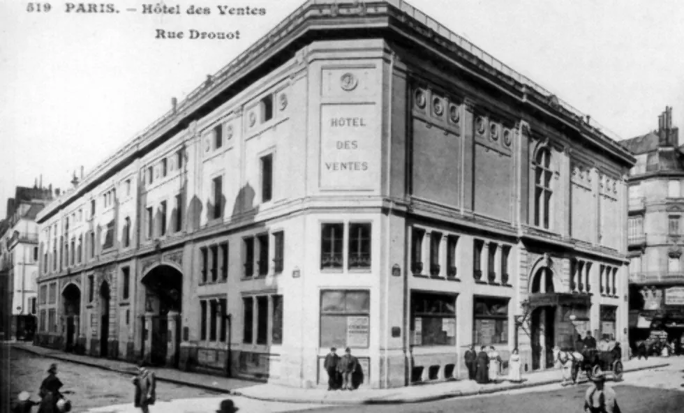 Corner of a four-story stone building with two men standing in front