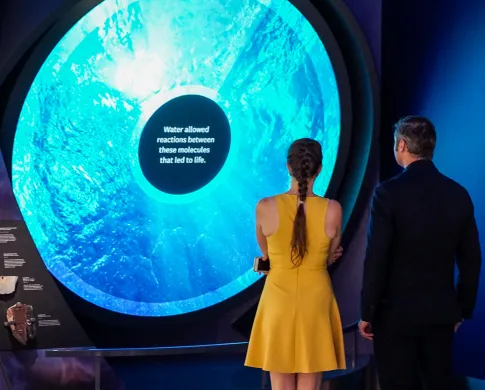 Two people standing in front of a blue circular screen