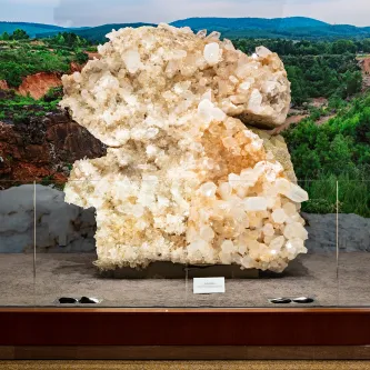 Huge cluster of sparkling white and clear quartz crystals on a platform in an exhibit.